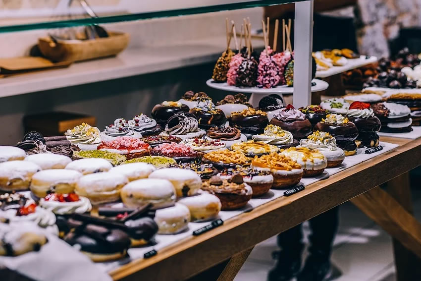 Présentation de pâtisseries en vitrine avec des plats plexi